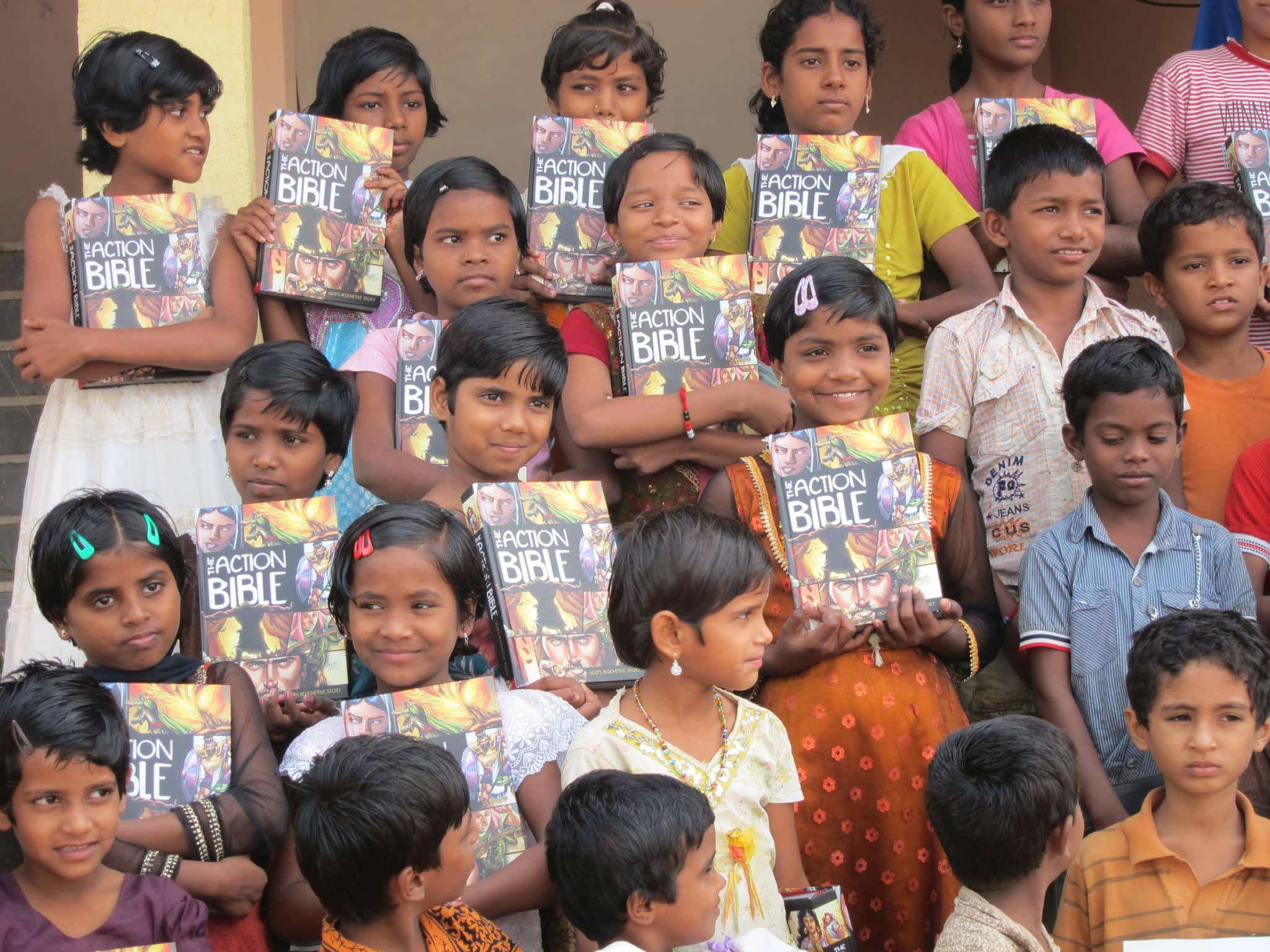 group of children holding up the action bible